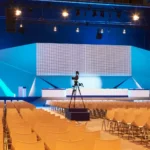 Scène de salle de conférence parfaitement éclairée de manière globale par des projecteurs Fresnel LED suspendus en hauteur.