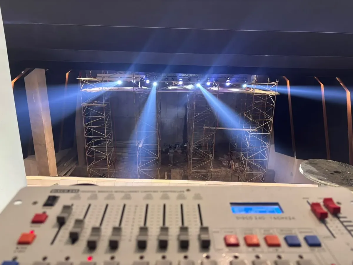 Console DMX en régie au premier plan, faisceaux des lyres sur la scène de l'amphithéâtre en arrière-plan
