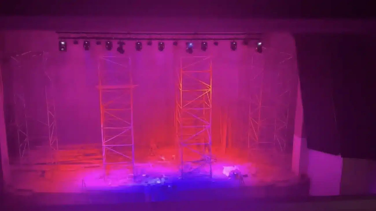 Scène de l'amphithéâtre d'une école à El Jadida baignée de lumière magenta par les lyres wash, pont lumière visible en hauteur