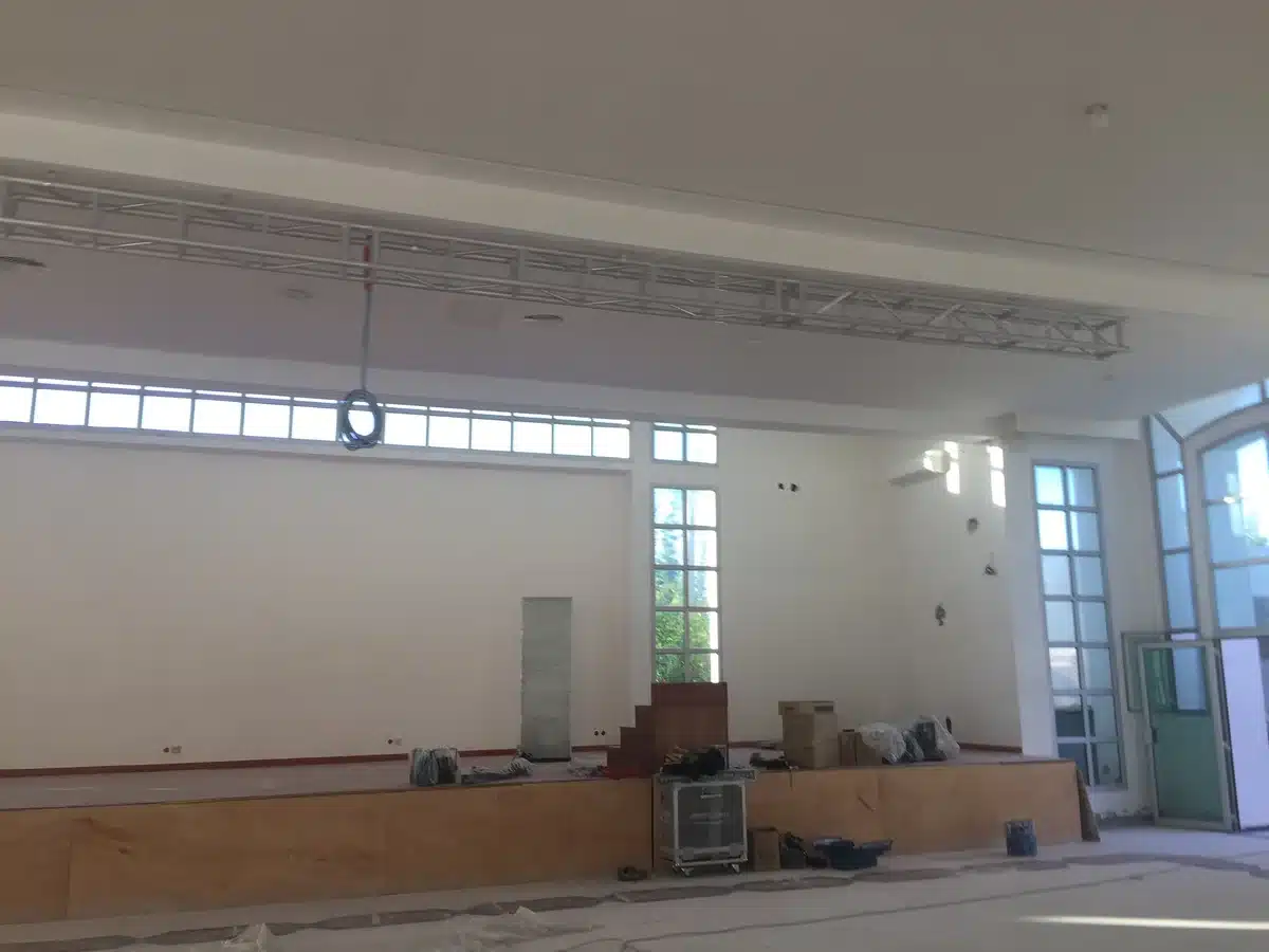 Pont en truss aluminium suspendu au-dessus de la scène, salle encore vide avant l'accrochage