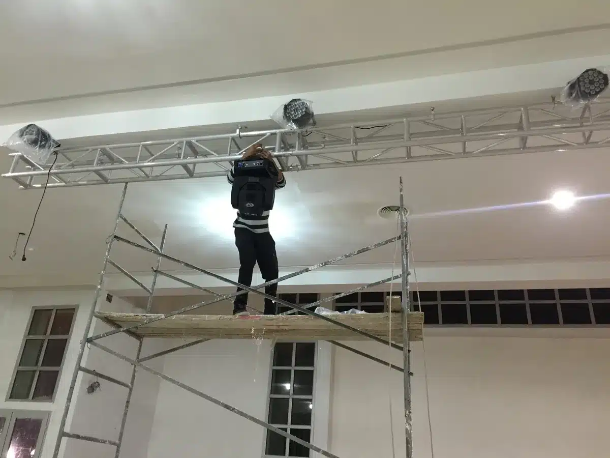 Technicien accrochant une lyre Beam au pont truss depuis un échafaudage
